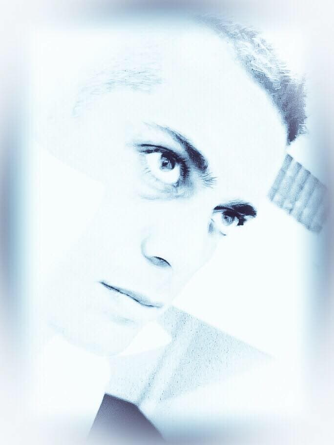 High-key, blue-tinted portrait of a young man with a contemplative expression looking slightly upward.